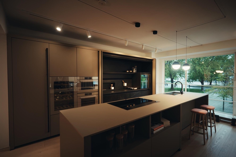 Beige next125 kitchen with bar stools in front of a large window overlooking Munich