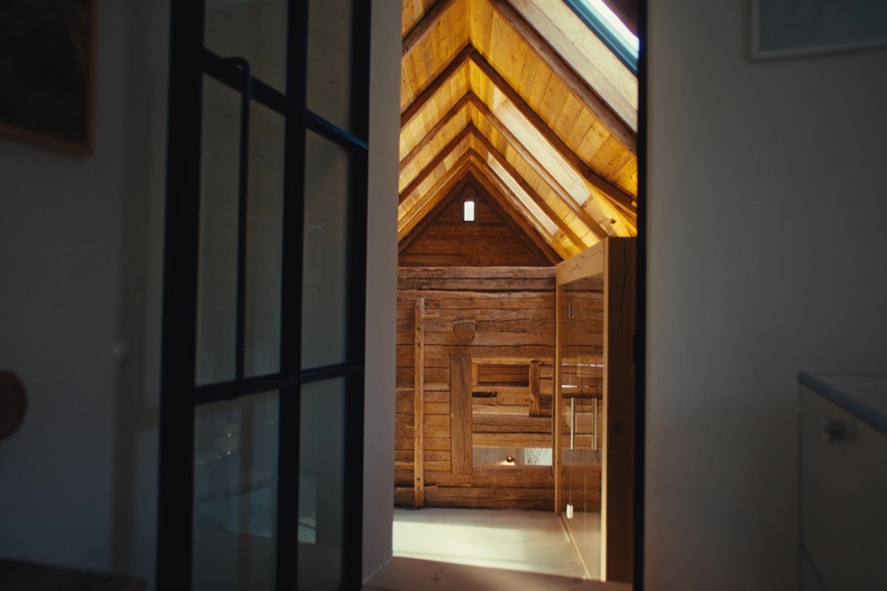 View through a doorway into an open room with an old timber-beam ceiling